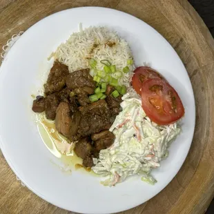 Stew brown chicken with white rice coleslaw and tomato.