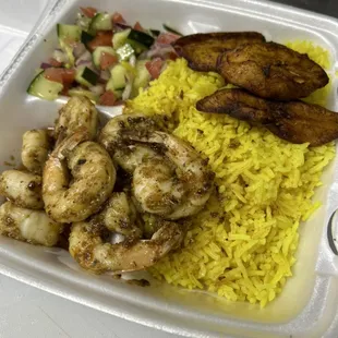 Garlic jerk shrimp plate with plantain and cucumber tomato and red onions salad.