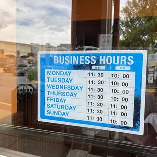 a business hours sign in a window