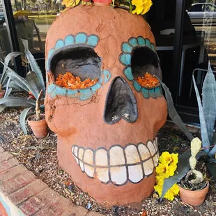 An enormous calavera sits in the planter by the main entrance.