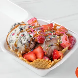 Two scoops of SolDias Ice Cream with fresh-cut strawberries, cajeta, lechera, and sprinkles served on a homemade waffle bowl.