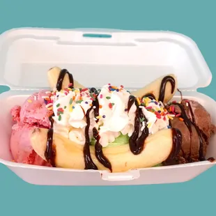 a banana split in a container with ice cream and sprinkles
