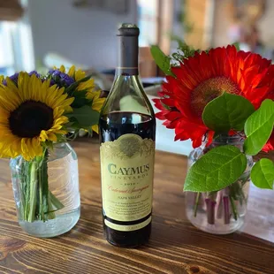 a bottle of wine and a vase of sunflowers