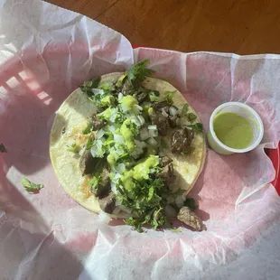 Carne asada taco on corn tortilla with cilantro, onion, and salsa.