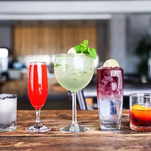 a variety of cocktails on a wooden table