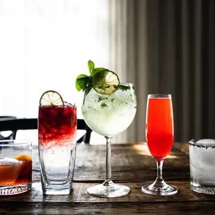 a variety of cocktails on a wooden table