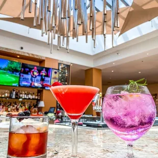 two cocktails on a bar with a television in the background