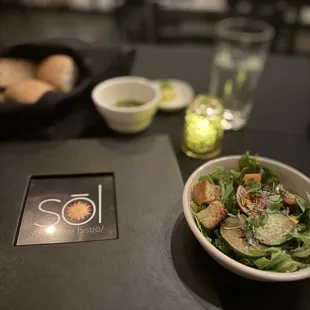 Salad in the front and bread basket in the back with the garlic oil.