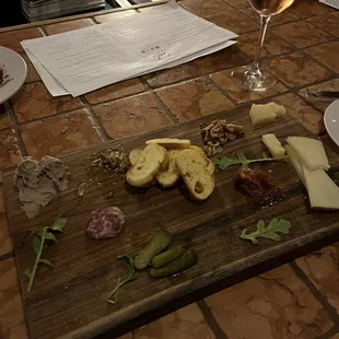 a wooden cutting board with a variety of cheeses and meats