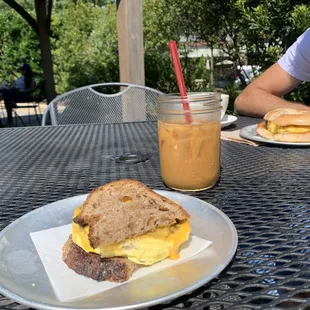 Egg sandwich with sausage on multigrain bread and an iced coffee