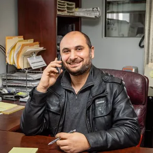a man sitting at a desk talking on a cell phone