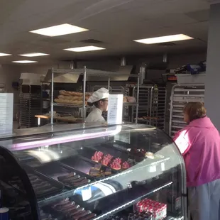 a woman standing in front of a bakery counter