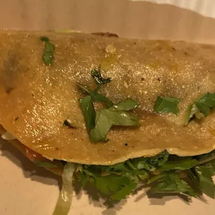 Messy taco covered in cilantro and had tomatoes in it