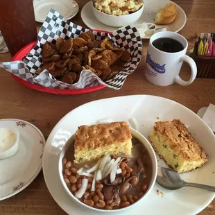a bowl of beans, a plate of cornbreads, a plate of cornbreads, and a cup of coffee