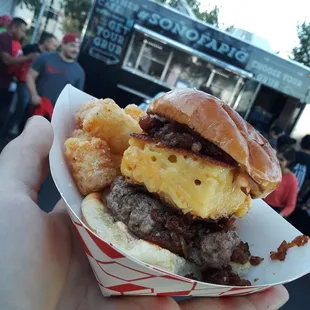 a person holding a burger and onion rings