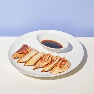 a plate of dumplings and a bowl of sauce