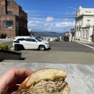 a hand holding a half eaten sandwich