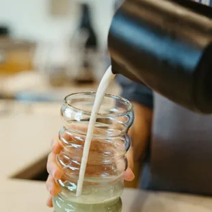 a person pouring milk into a jar