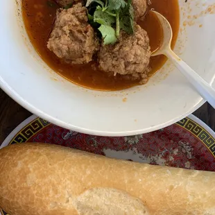 a bowl of soup with meatballs and bread