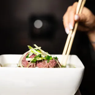 a bowl of food with chopsticks