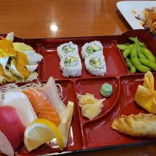 a tray of sushi and vegetables