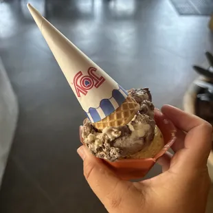 a hand holding a cone of ice cream