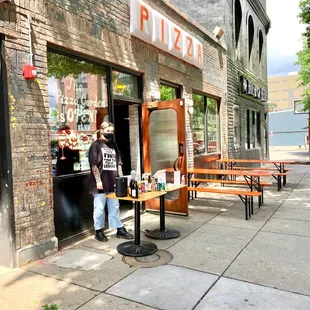a man standing in front of a pizza shop