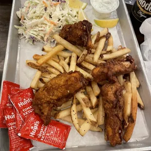a tray of fried chicken, fries, coleslaw and coleslaw slaw