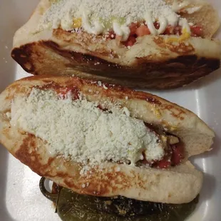 two hot dogs with cheese and pickles