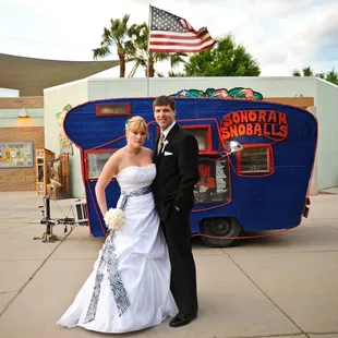 a bride and groom in front of a food truck