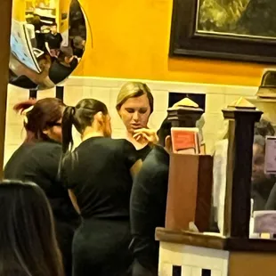 Looking at something on someone's phone. Not paying attention to customers.