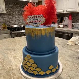 a blue cake with gold and red feathers