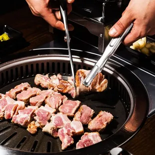 a person using tongs to cut meat