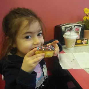 a little girl eating a donut