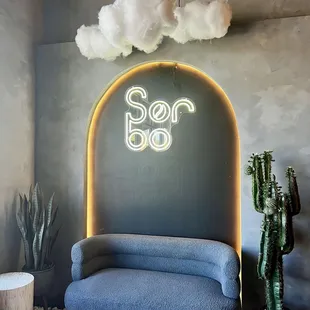 a blue couch with a neon sign above it