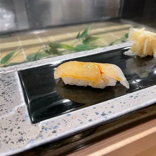 two pieces of sushi on a black plate