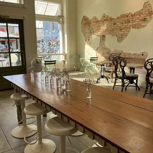 a long wooden table with white stools