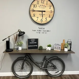 a bicycle leaning against a wall with a clock above it