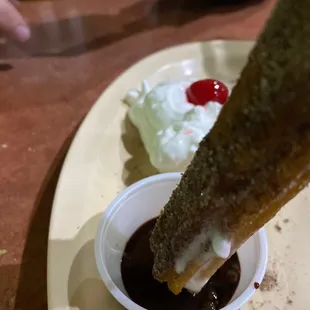 a donut dipped with chocolate sauce and whipped cream