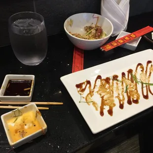 a plate of sushi with sauce and chopsticks