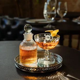 a glass of liquor and a decanter on a tray