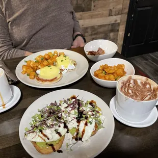 Eggs benny and avocado toast with home fries.