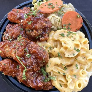 a plate of food with meat, pasta and carrots