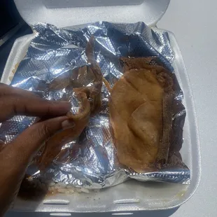 a person holding a piece of food in a styrofoam container