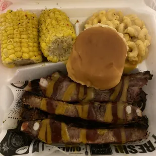 a hamburger, ribs, corn and macaroni