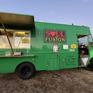 a green food truck parked in a parking lot