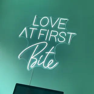 a neon sign that says love at first bite