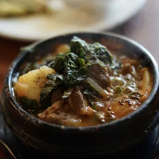 a bowl of stew with potatoes and greens