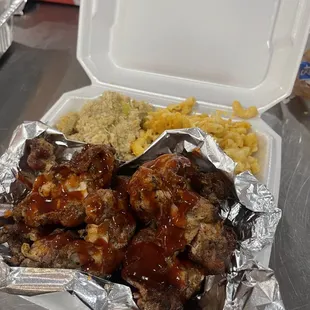 a container of ribs and rice with a side of macaroni and cheese