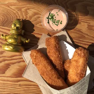 a basket of fried chicken sticks and a bowl of dip